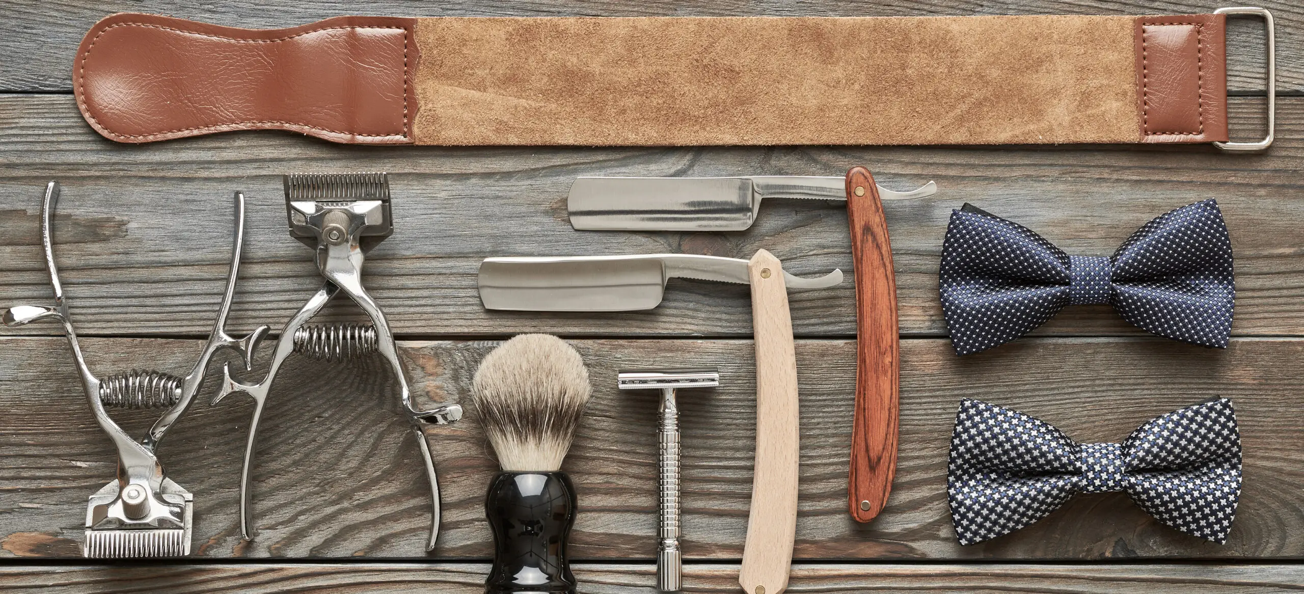 Vintage straight razors and shaving brushes arranged on wooden surface. Vintage straight razors and shaving brushes arranged on wooden surface.