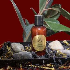 Amber bottle of aromatic oil surrounded by crystals and beads with green leaves.