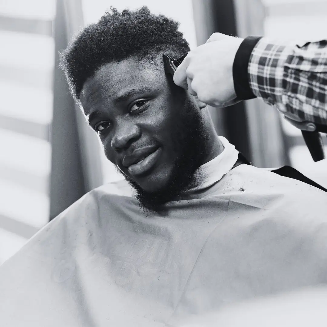 A man getting a haircut, smiling as the barber works. A man getting a haircut, smiling as the barber works.