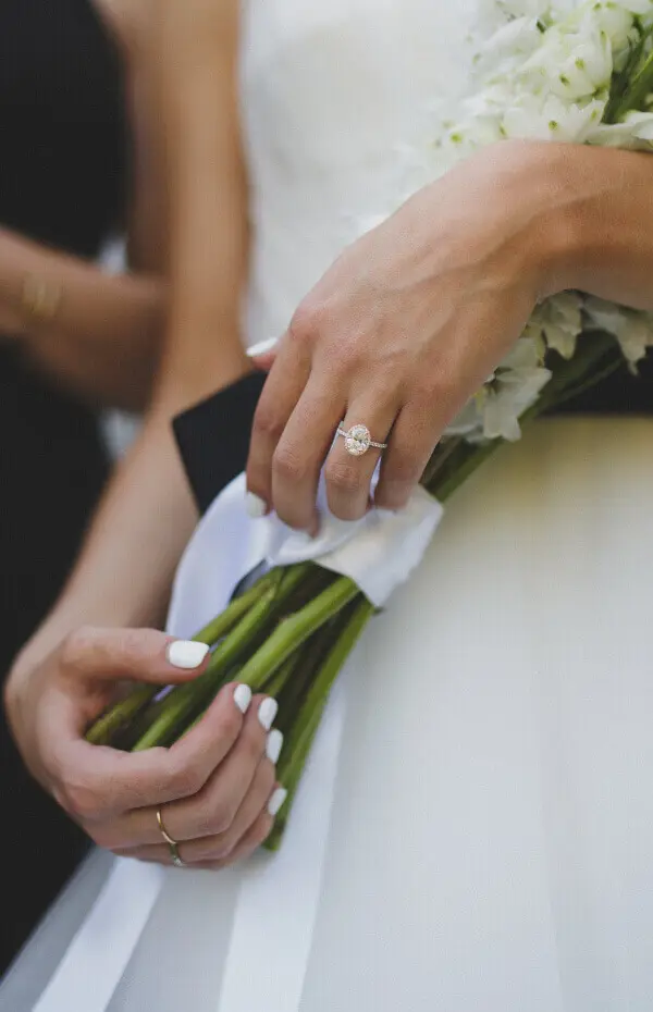 Close-up of a bride’s hands holding a bouquet and showing an engagement ring. Close-up of a bride's hands holding a bouquet and showing an engagement ring.
